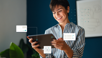 A woman looks smiling at her screen and a logo in the upper left corner says AI