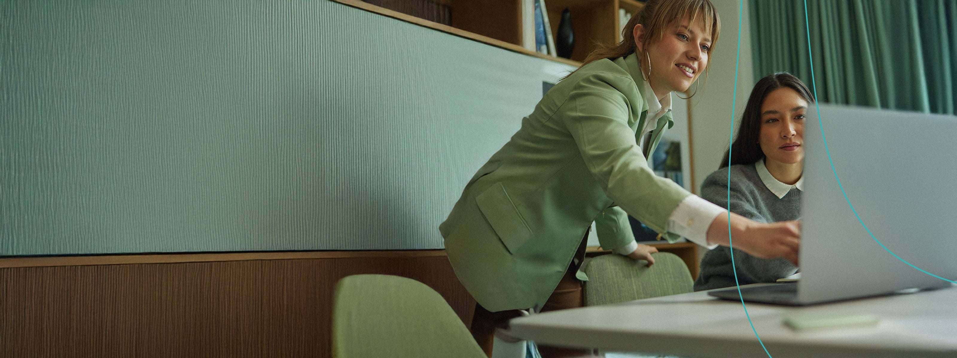 Two women working at a table and looking at a laptop screen