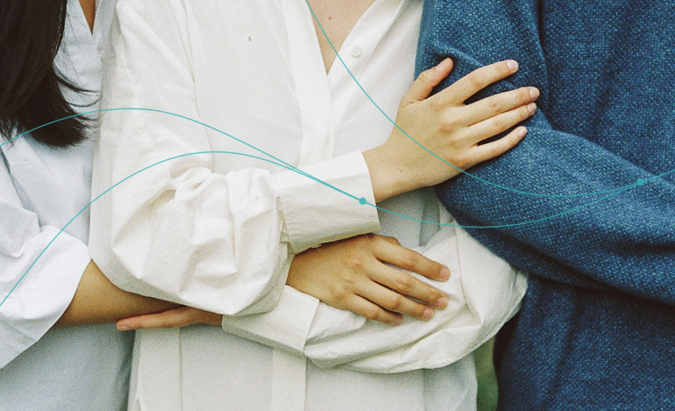 Two people embracing, one in a white outfit and the other in a blue sweater.