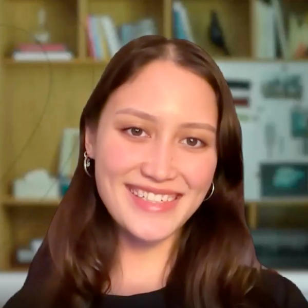 Woman with long brown hair smiling in front of a bookshelf