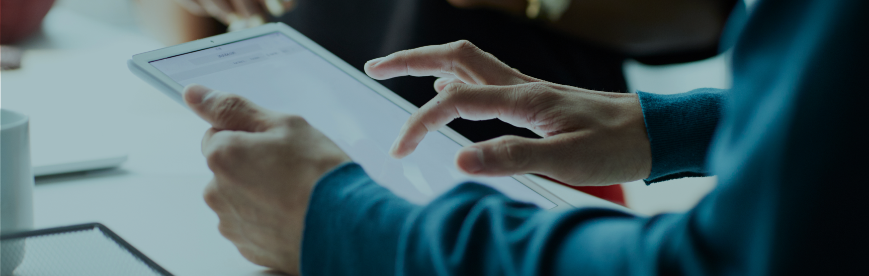Two masculine hands holding and scrolling on a large, white tablet.