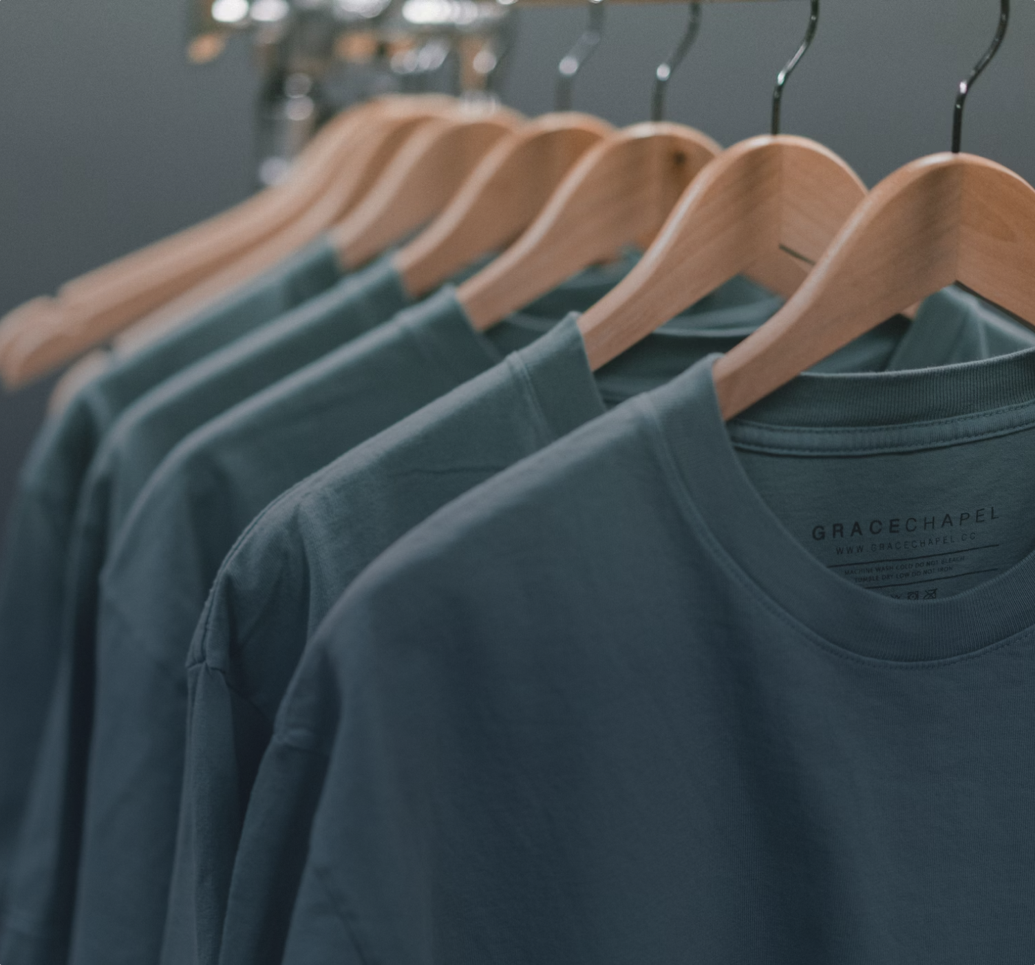 a rack of blue, sustainably sourced and manufactured long-sleeve t-shirts on coat hangers.